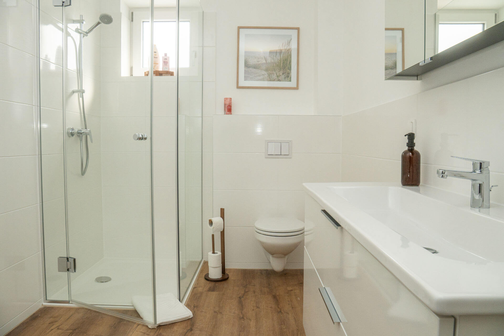 Helles Badezimmer mit Glasdusche, Waschtisch und Holzboden